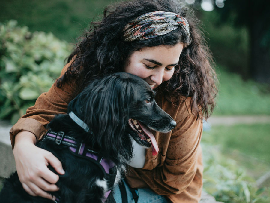 Wellness Care Woman hugs her black dog.