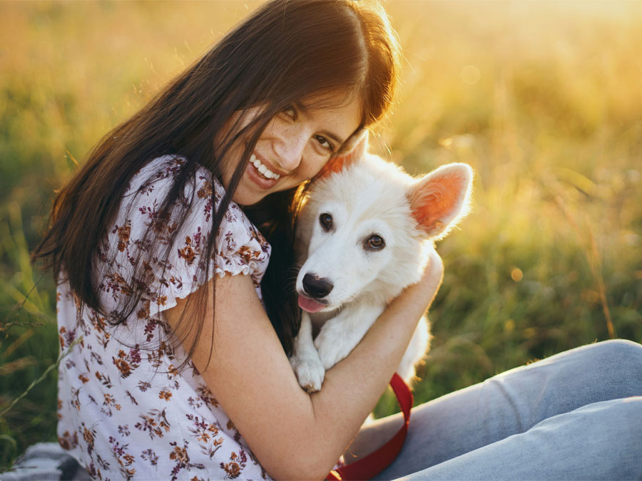 Woman hugs fluffy white puppy.