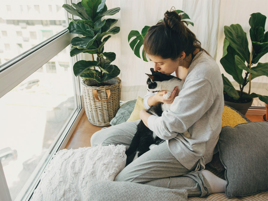 Woman hugging black and white cat.