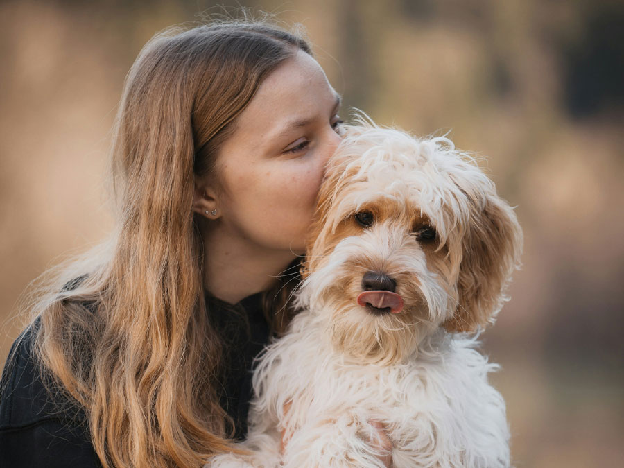 Woman kisses fluffy dog.