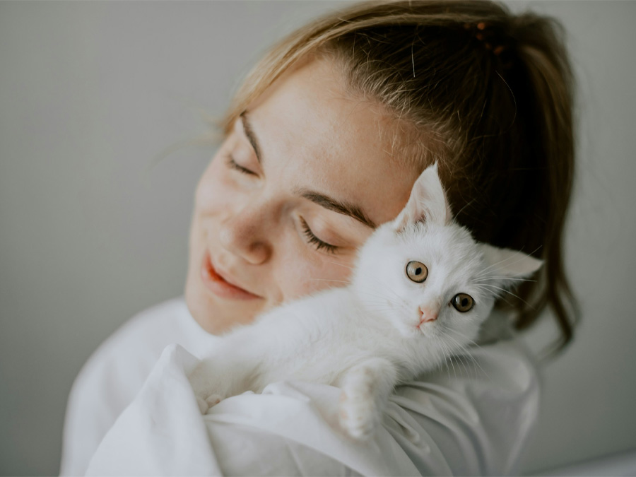 Woman lovingly holds white kitten.