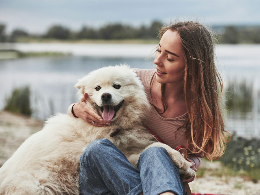 Woman cuddling happy, fluffy dog.
