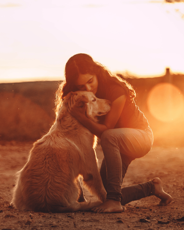 woman hugging a dog outside at sunset